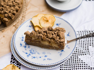 Rohköstlicher Apfelkuchen, ein Stück mit Streuseln und Apfelschichten auf dem Teller