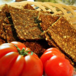 Glutenfreies Rohkost Brot in Scheiben im Korb mit frischen Tomaten