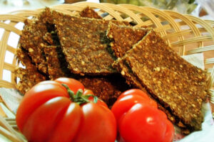 Glutenfreies Rohkost Brot in Scheiben im Korb mit frischen Tomaten