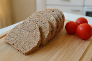Rohkost Brot aus Mandeltrester in Scheiben mit Tomaten auf dem Holzbrett