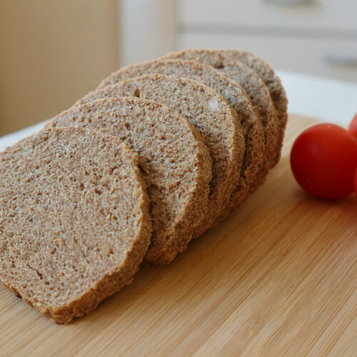 Rohkost Brot 4 Rohkost Brot aus Mandeltrester in Scheiben mit Tomaten auf dem Holzbrett