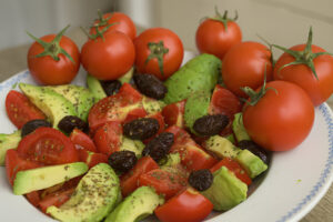 Tomaten Avocado Salat mit Oliven und frischem Basilikum in einer Schüssel