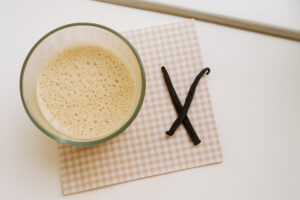 Schaumige Vanille-Milch im Glas mit Vanilleschoten