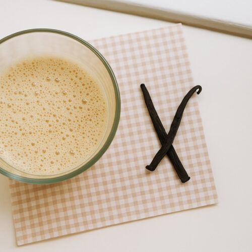 Schaumige Vanille-Milch im Glas mit Vanilleschoten